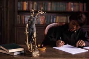 A focused judge writing legal notes beside a Lady Justice statue symbolizing truth and fairness to help win a court case.