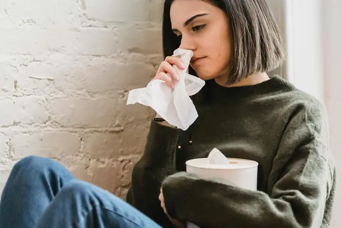 Sad woman wiping her nose with tissue, reflecting emotional distress from Facebook online dating mistakes like rushing into emotional investment or ignoring red flags.