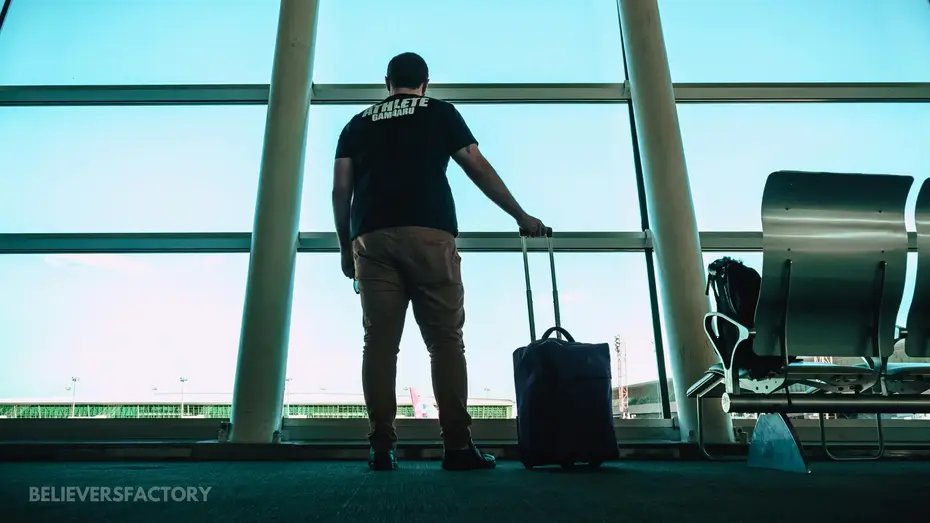 A man holding luggage bag at the airport waiting stand.