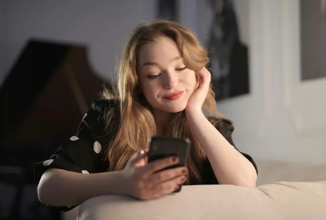 Woman smiling while looking at her phone, enjoying a conversation