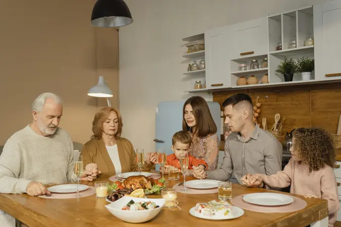 Family holding hands in prayer around a Christmas dinner table