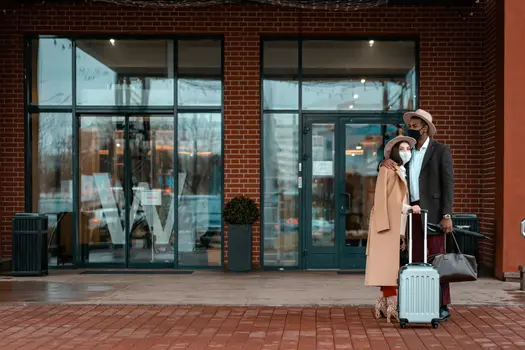Dating as an immigrant couple arriving at hotel with suitcases and masks