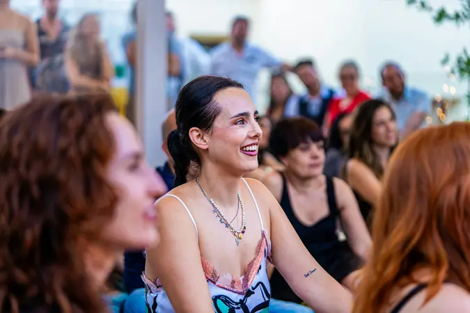 A group of people attentively listening and smiling during a social event focused on meeting potential partners.