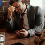 A man looking stressed during a group meetup — a possible awkward moment while meeting potential partners through friends