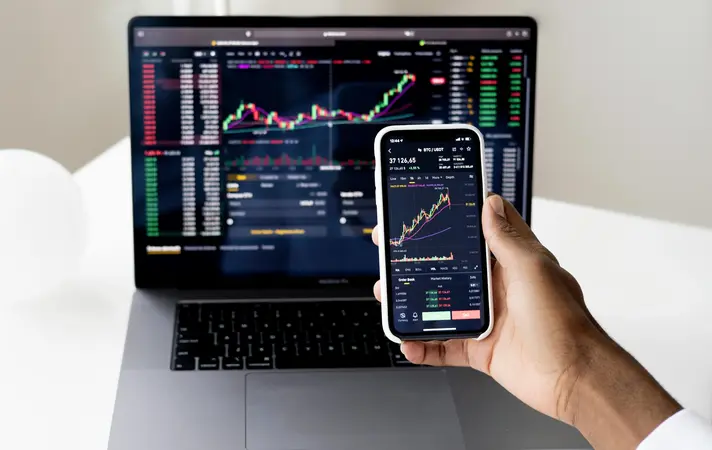 A beginner forex trader analyzing price movements on a mobile and laptop trading platform simultaneously